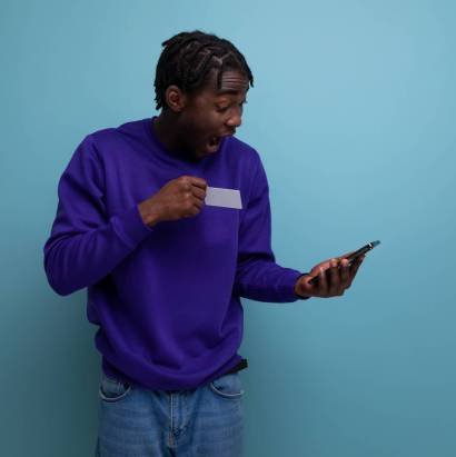 satisfied american young man with dreadlocks with a mobile phone pays the bill.
